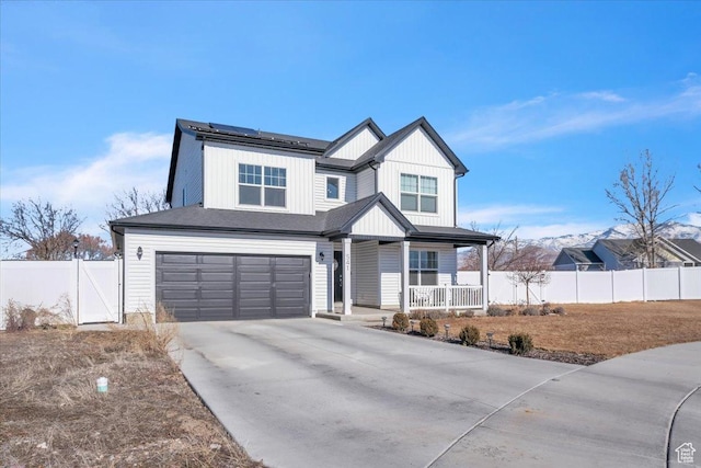 view of front of property with fence, a porch, roof mounted solar panels, driveway, and an attached garage