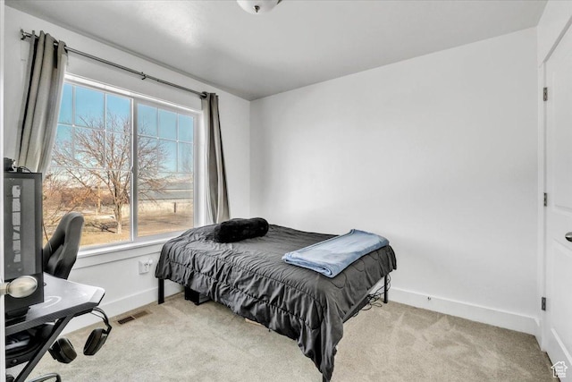 bedroom featuring visible vents, light colored carpet, and baseboards
