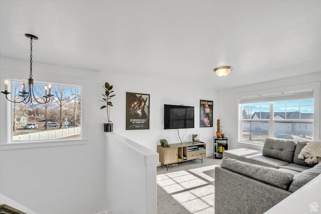 living area featuring a chandelier, baseboards, and carpet