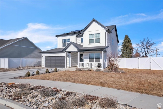 view of front of home with solar panels, fence, a porch, concrete driveway, and a gate