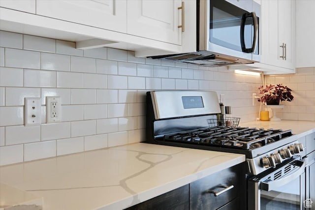 kitchen with light stone counters, tasteful backsplash, appliances with stainless steel finishes, and white cabinetry