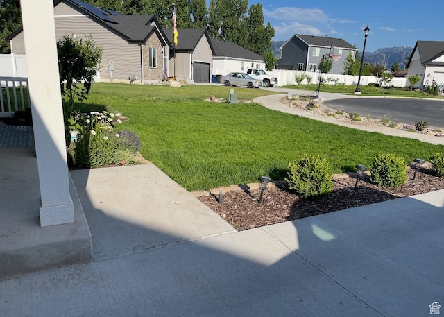 view of yard featuring a garage, a residential view, and fence