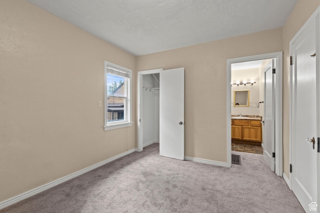 385 N 400 E, Logan, UT 84321 - unfurnished bedroom featuring carpet flooring, baseboards, connected bathroom, a sink, and a textured ceiling