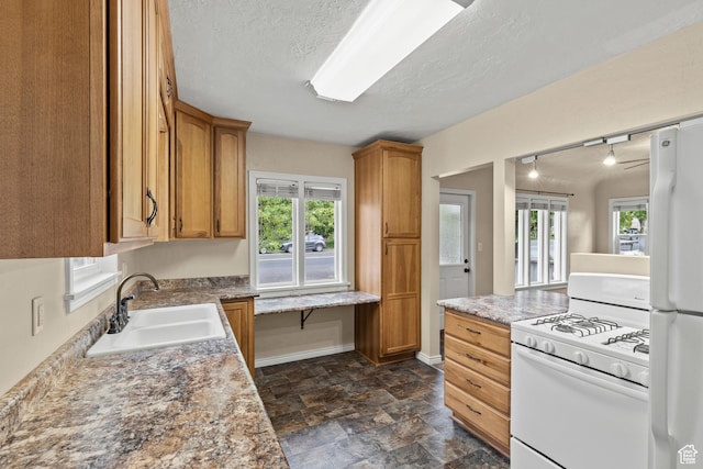 385 N 400 E, Logan, UT 84321 - kitchen featuring white appliances, a sink, dark stone finish flooring, plenty of natural light, and a textured ceiling