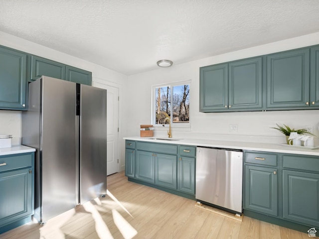 kitchen featuring sink, refrigerator, a textured ceiling, stainless steel refrigerator, and light hardwood / wood-style floors
