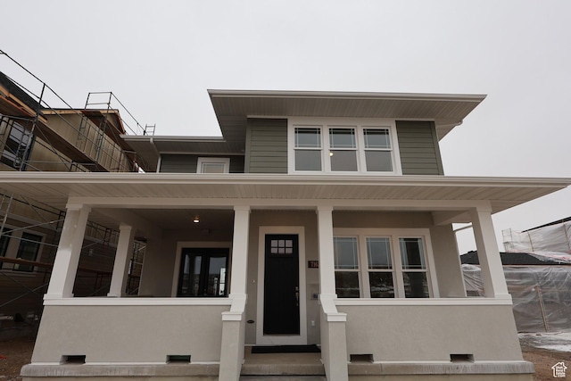 view of front facade featuring covered porch, crawl space, and stucco siding