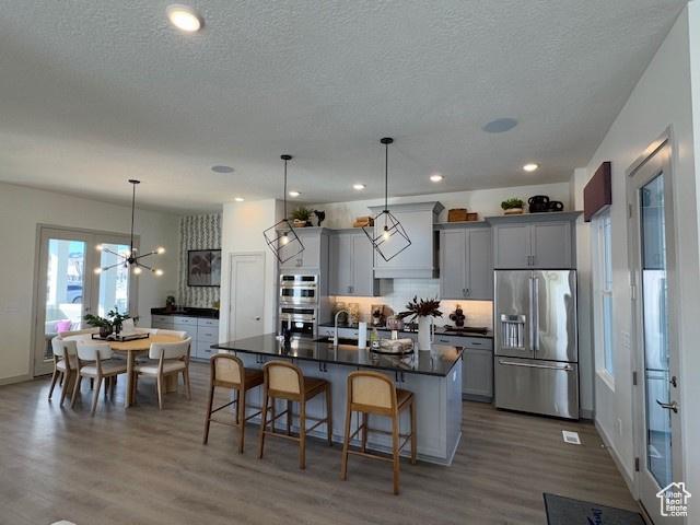 kitchen featuring dark countertops, appliances with stainless steel finishes, a breakfast bar area, and gray cabinetry