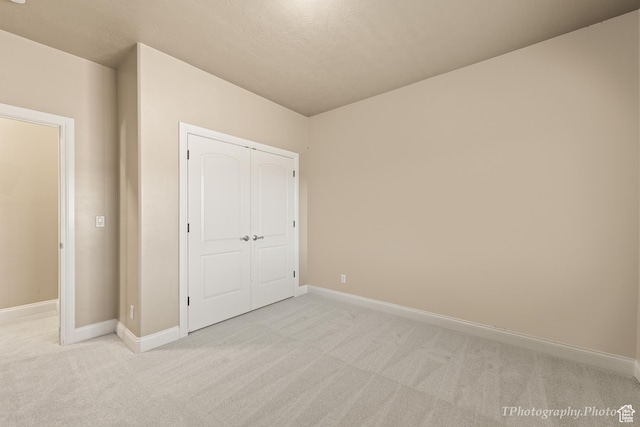 unfurnished bedroom featuring light carpet and a closet