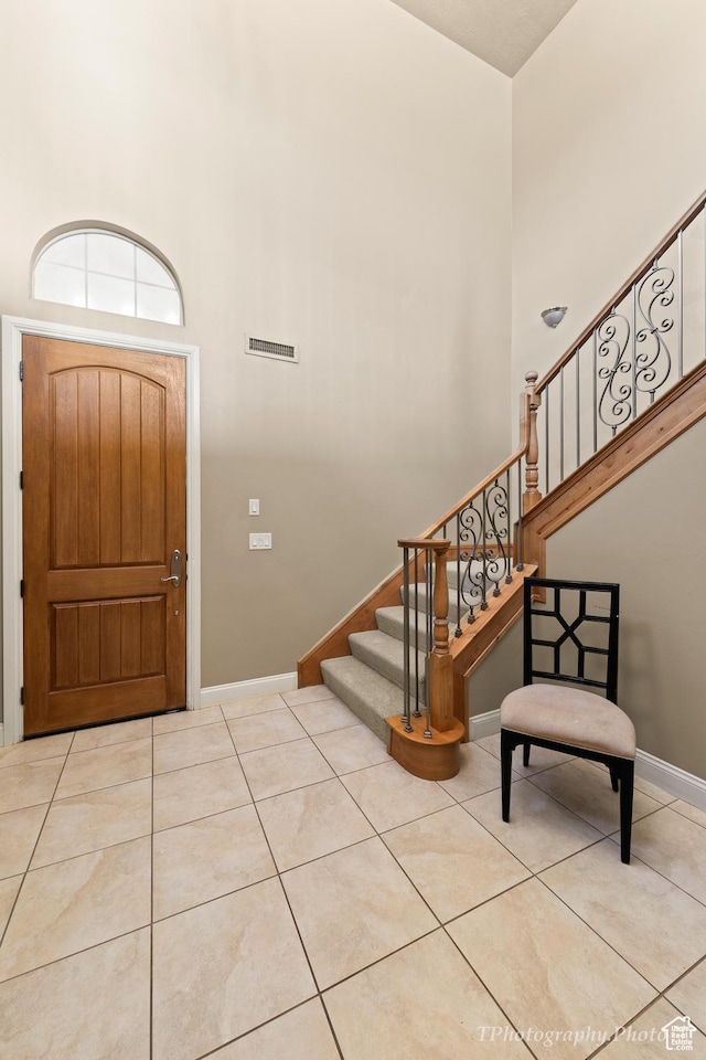 tiled entryway featuring a towering ceiling