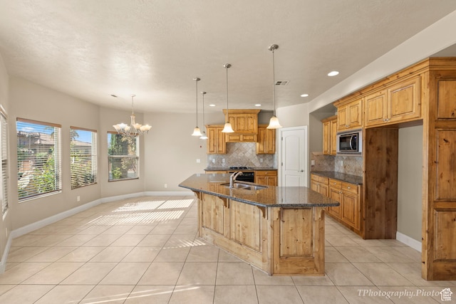kitchen featuring light tile patterned flooring, sink, stainless steel microwave, and decorative backsplash