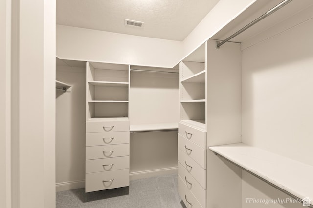 walk in closet featuring light colored carpet