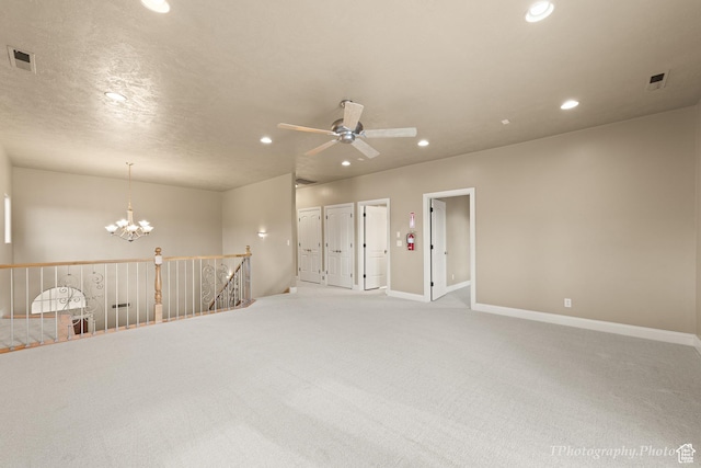 carpeted empty room with ceiling fan with notable chandelier