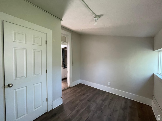 empty room with a textured ceiling, baseboards, and dark wood-style floors