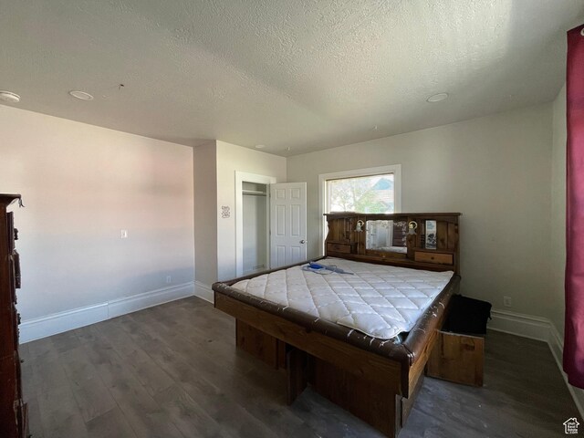 bedroom with wood finished floors, a textured ceiling, and baseboards