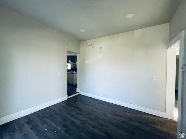 spare room featuring baseboards, dark wood-style flooring, and recessed lighting