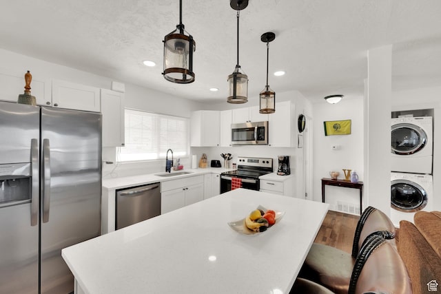870 E Vics Rd, Sandy, UT 84094 - kitchen featuring sink, decorative light fixtures, appliances with stainless steel finishes, stacked washing maching and dryer, and white cabinets