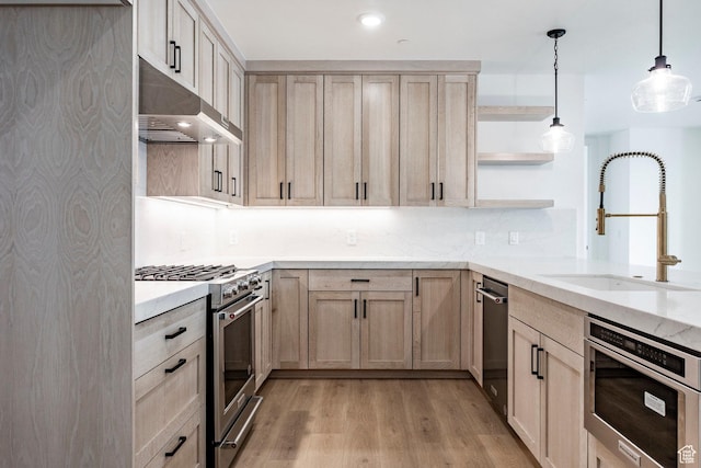 kitchen featuring light brown cabinetry, sink, stainless steel range, pendant lighting, and light hardwood / wood-style floors