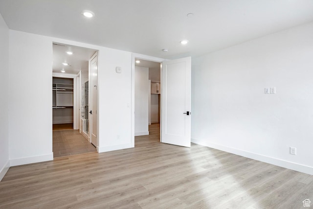 unfurnished bedroom featuring a walk in closet, light hardwood / wood-style floors, and a closet