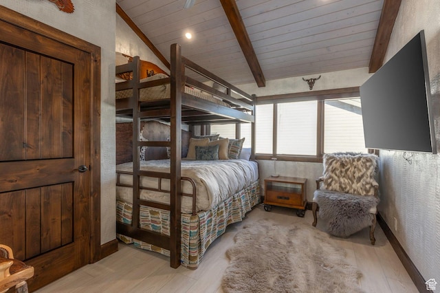 bedroom featuring wooden ceiling, vaulted ceiling with beams, baseboards, light wood-style floors, and a textured wall