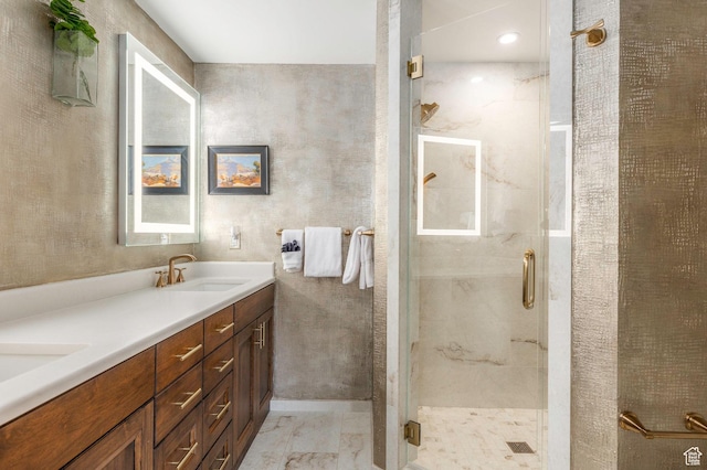full bath with marble finish floor, double vanity, a stall shower, and a sink