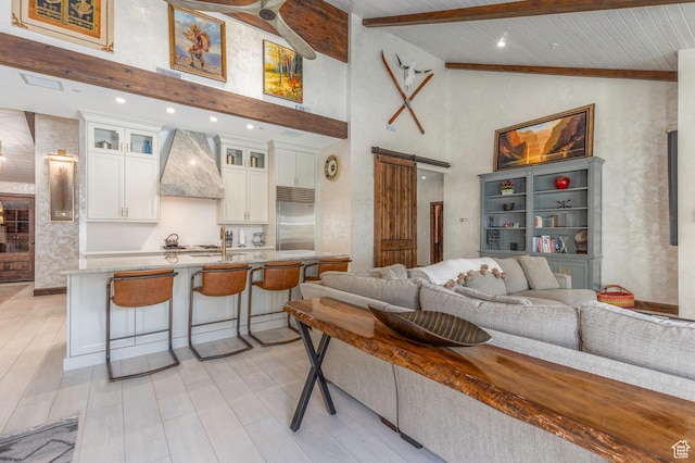 living area with light wood-style flooring, high vaulted ceiling, a barn door, and beamed ceiling