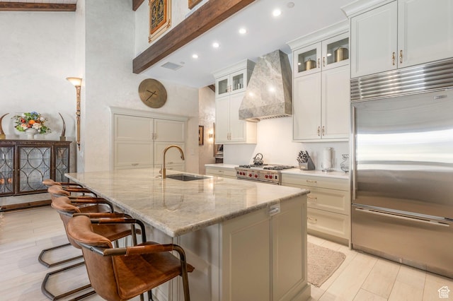 kitchen featuring visible vents, a sink, an island with sink, premium appliances, and custom range hood