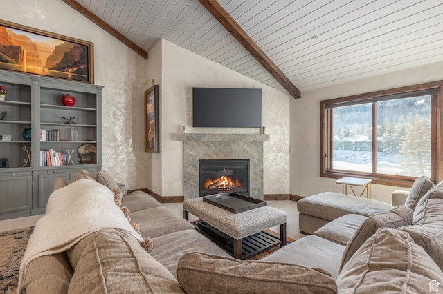 living room featuring baseboards, lofted ceiling, and a glass covered fireplace