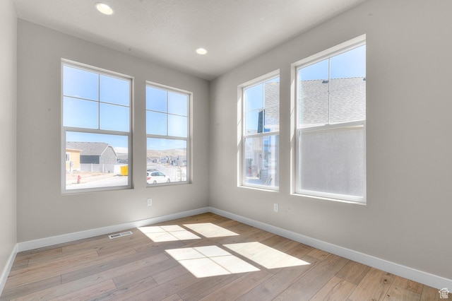 spare room with visible vents, baseboards, and light wood-type flooring