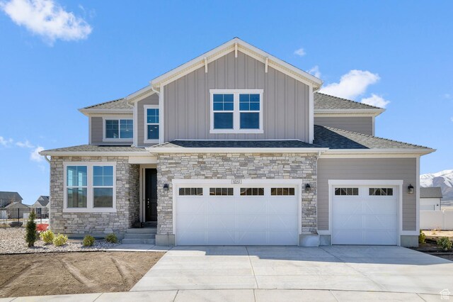 view of front of house featuring driveway, a garage, stone siding, and board and batten siding