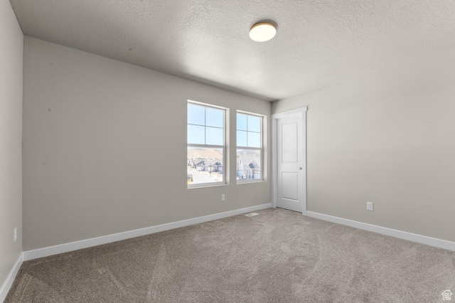 carpeted empty room with visible vents, baseboards, and a textured ceiling