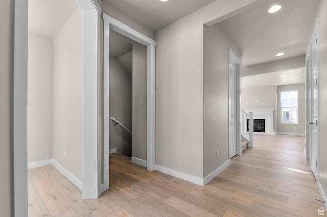 corridor featuring light wood-style flooring, an upstairs landing, baseboards, and recessed lighting