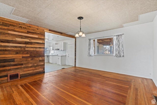 interior space featuring an inviting chandelier, wooden walls, and hardwood / wood-style flooring