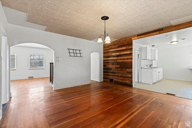 interior space with a notable chandelier, dark hardwood / wood-style floors, sink, and wood walls