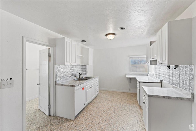 kitchen featuring sink, dishwasher, white cabinetry, backsplash, and a textured ceiling