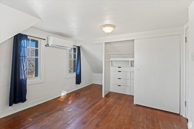 additional living space featuring vaulted ceiling, dark hardwood / wood-style floors, and a wall mounted AC