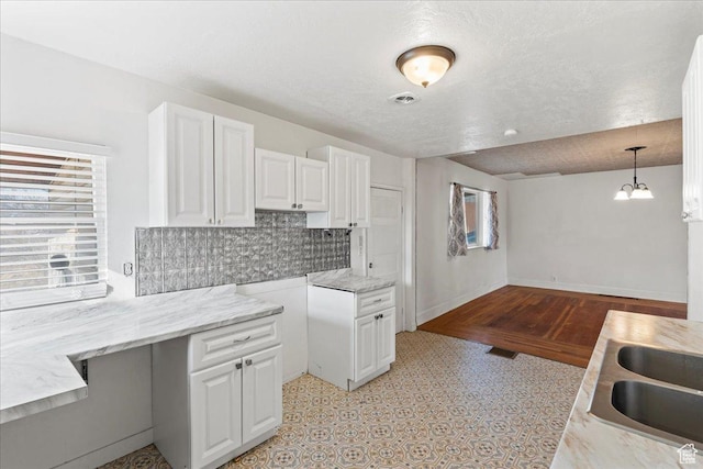kitchen with sink, a textured ceiling, hanging light fixtures, backsplash, and white cabinets
