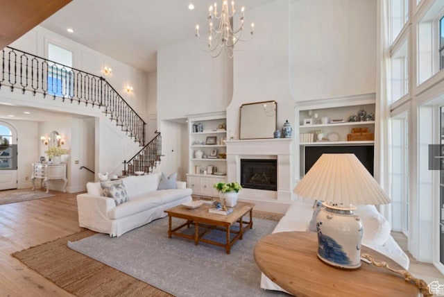 living room with a high ceiling, plenty of natural light, light wood-type flooring, and a chandelier