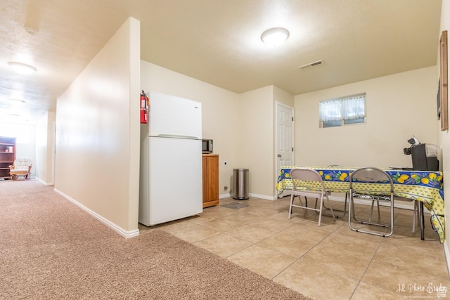 interior space with white fridge and light tile patterned floors