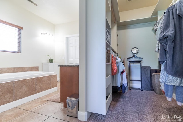 bathroom with tile patterned flooring, vanity, and tiled bath