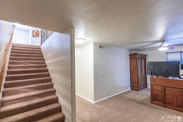 stairs featuring ceiling fan, carpet, and a textured ceiling