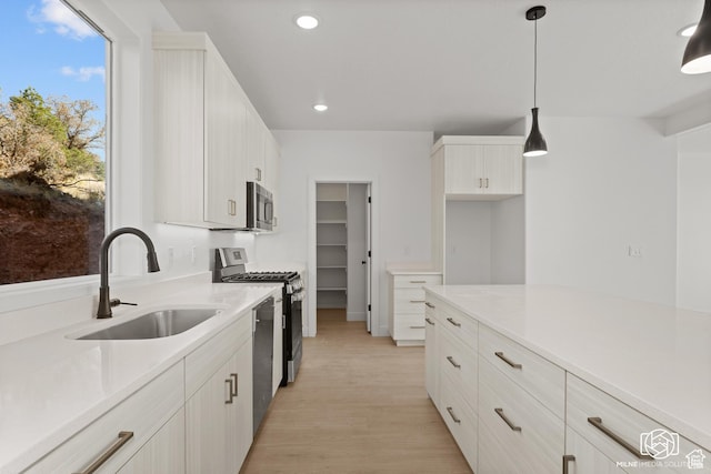 665 E 2015 N Unit 5C, Cedar City, UT 84721 - kitchen with sink, light hardwood / wood-style flooring, appliances with stainless steel finishes, hanging light fixtures, and white cabinets