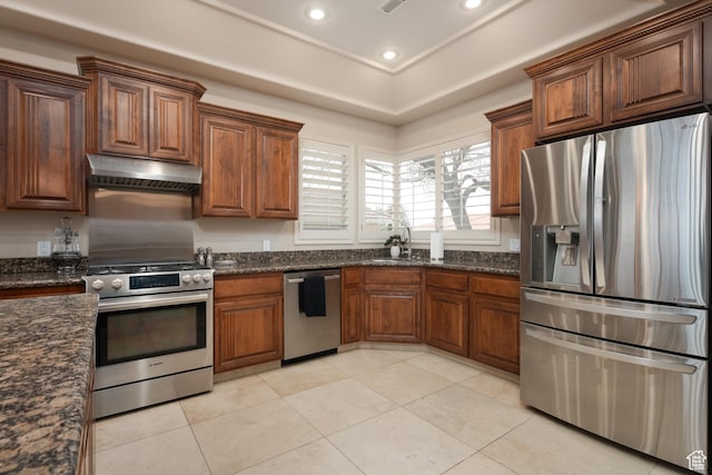 kitchen featuring sink, light tile patterned floors, dark stone counters, and appliances with stainless steel finishes