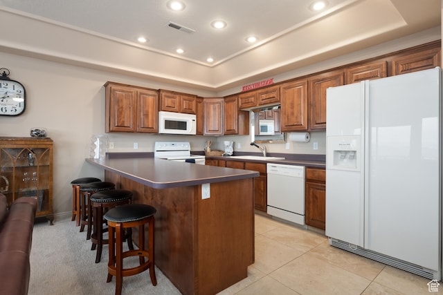 kitchen with light tile patterned flooring, sink, a breakfast bar area, a raised ceiling, and white appliances