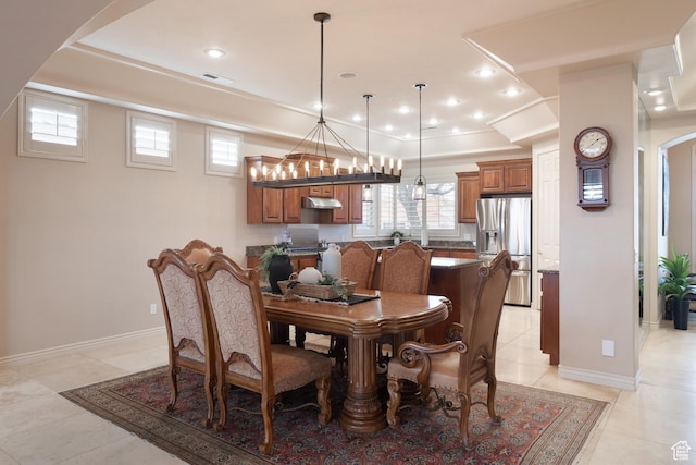 dining space with light tile patterned flooring and a tray ceiling