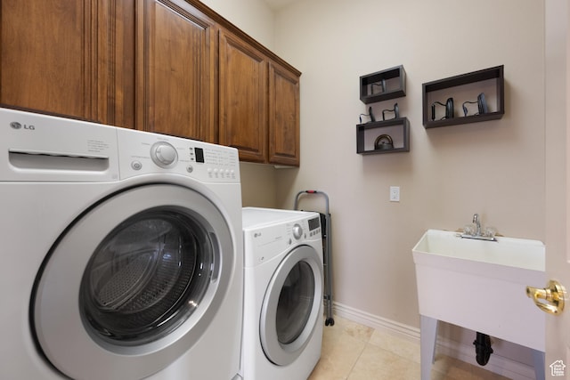 clothes washing area featuring cabinets, light tile patterned floors, and washing machine and clothes dryer