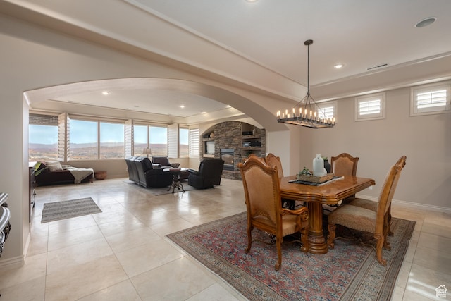tiled dining area featuring a fireplace and a notable chandelier