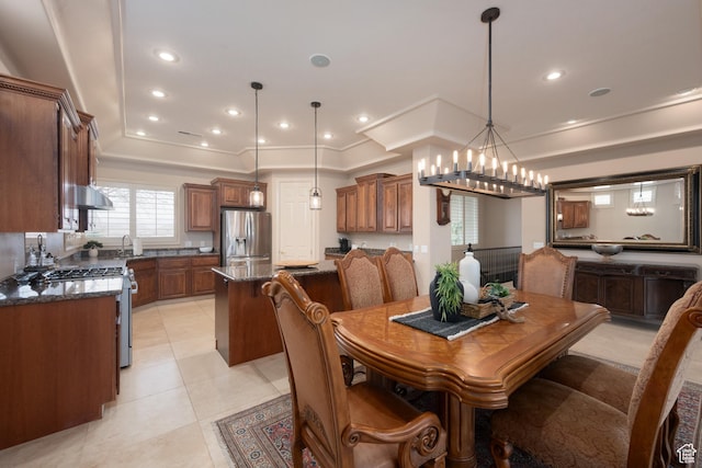 tiled dining area featuring an inviting chandelier and a tray ceiling