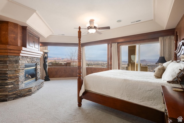 carpeted bedroom featuring ceiling fan and a fireplace