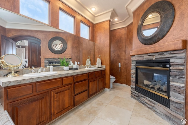 bathroom with crown molding, tile patterned flooring, vanity, a fireplace, and toilet