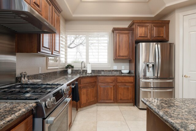 kitchen featuring stainless steel appliances, sink, light tile patterned floors, and dark stone countertops